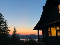 the sun is setting behind a house with mountains in the background