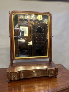 an antique wooden desk with a mirror on top