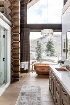 a bathroom with a tub, sink and large window overlooking the snow - capped mountains