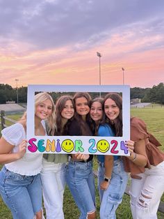 four girls holding up a sign that says senior 2012 with the sun setting in the background