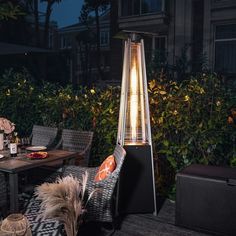 an outdoor patio heater sitting on top of a wooden deck next to a table and chairs