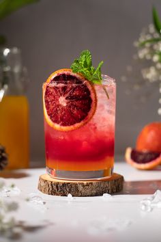 a blood orange cocktail with mint garnish on the rim