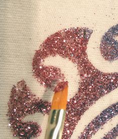 a close up of a brush with some glitter on it next to a piece of fabric