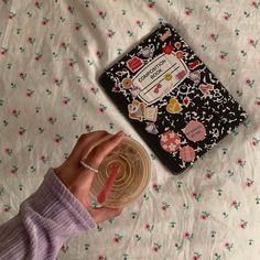 a person is holding a plastic object in front of a book on top of a bed