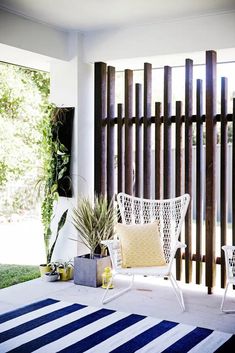 a white chair sitting on top of a blue and white rug next to a wooden fence