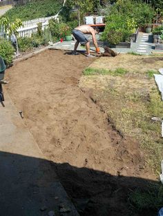 a man is digging in the dirt with a wheelbarrow on his back yard