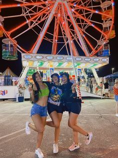 three girls standing in front of a ferris wheel