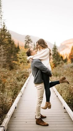 a man holding a woman on top of a bridge