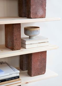 some books are stacked on top of each other in a book shelf with two vases