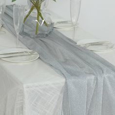 the table is set with silverware and flowers in glass vases on each side