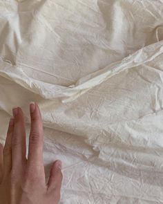 a person's hand reaching for something on a white sheet