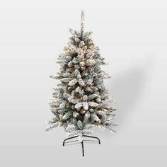 a white christmas tree with lights and snow on the branches is shown in front of a gray background