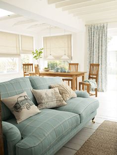 a living room filled with furniture and windows covered in roman blind shades on top of them