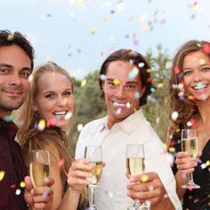 a group of people holding wine glasses with confetti in the air behind them