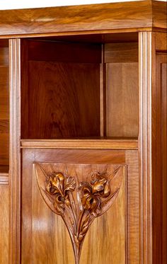 a wooden bookcase with carvings on the front and side panels, including an open door