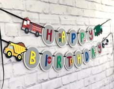 a happy birthday banner on a brick wall with construction trucks and firetrucks