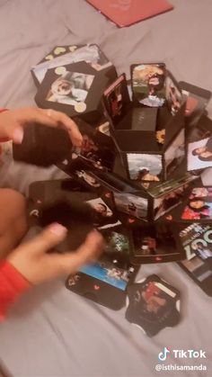 a person sitting on top of a bed next to a pile of cards and remotes