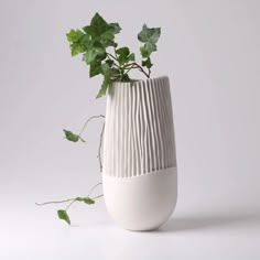 a white vase with green leaves in it