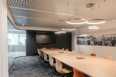 an empty conference room with long tables and chairs in front of a flat screen tv