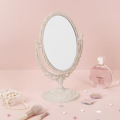 a white vanity mirror sitting on top of a table next to a bottle of perfume