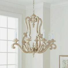 a chandelier hanging from the ceiling in a room with white walls and windows