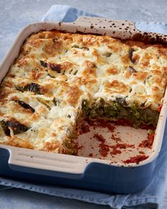 a casserole with broccoli, cheese and sauce in a blue dish