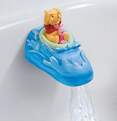 a winnie the pooh bathtub toy floating on top of a blue wave with water coming out of it