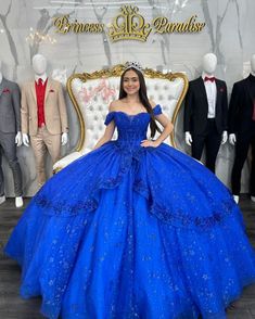 a woman in a blue ball gown standing next to mannequins