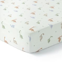 an image of a baby crib mattress with dinosaurs on it's coverlet