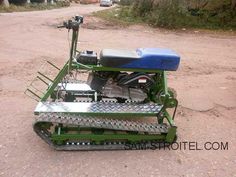 a green tractor with a blue and white mower attached to it's back