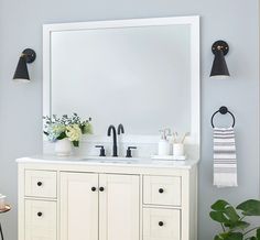 a white bathroom vanity with two black lights on the wall and a mirror above it