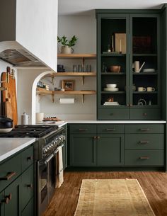 a kitchen with green cabinets and white counter tops, wood flooring and open shelving