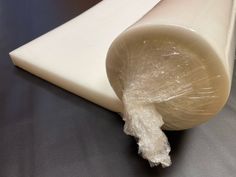 a piece of white plastic sitting on top of a black table next to a roll of paper