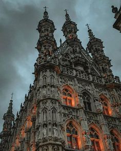 an ornate building lit up at night with orange lights on the windows and dark clouds in the background