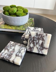 three pieces of soap sitting on top of a table next to a bowl of broccoli