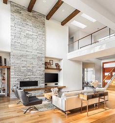 a living room filled with furniture and a tall stone wall behind the couch is a staircase