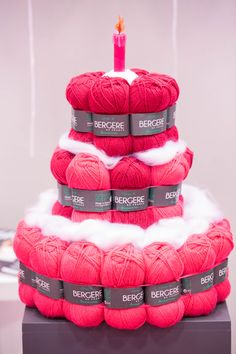 red balls of yarn stacked on top of each other with a lit candle in the middle