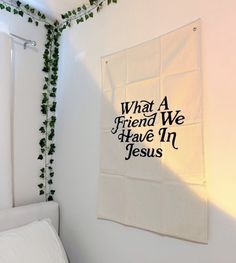 a white bed sitting next to a wall covered in green ivys and a sign that says, what a friend we have in jesus