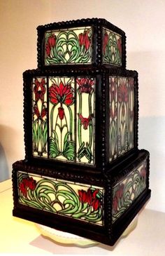 a three tiered stained glass vase sitting on top of a table