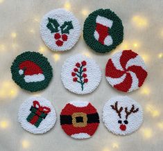 knitted christmas ornaments are arranged on a white surface with lights in the back ground