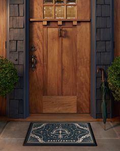 a wooden door with an umbrella and potted plants on the front step next to it