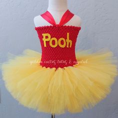 a red and yellow dress with pooh written on the front, sitting on a mannequin