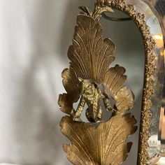 an ornate gold leaf and acorn decoration in front of a mirror