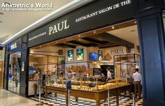 the interior of a restaurant with people walking in front of it and food on display