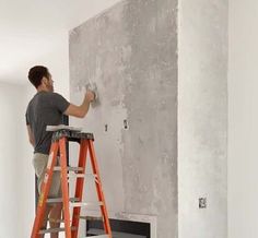 a man standing on a step ladder painting the walls in a room that is being remodeled