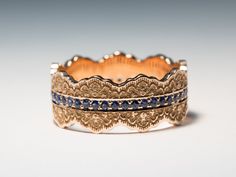 two gold rings with blue sapphires on each side and an engraved band in the middle