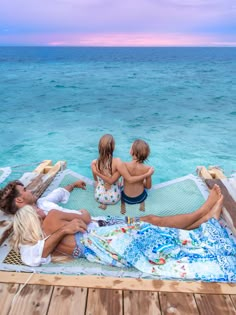 three people are sitting on a raft in the ocean with their backs to each other