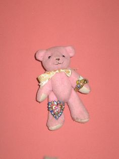 a pink teddy bear hanging from the side of a wall with other items on it