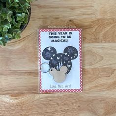 a mickey mouse keychain on a wooden table next to a potted plant