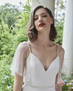 a woman wearing a wedding dress with sheer sleeves